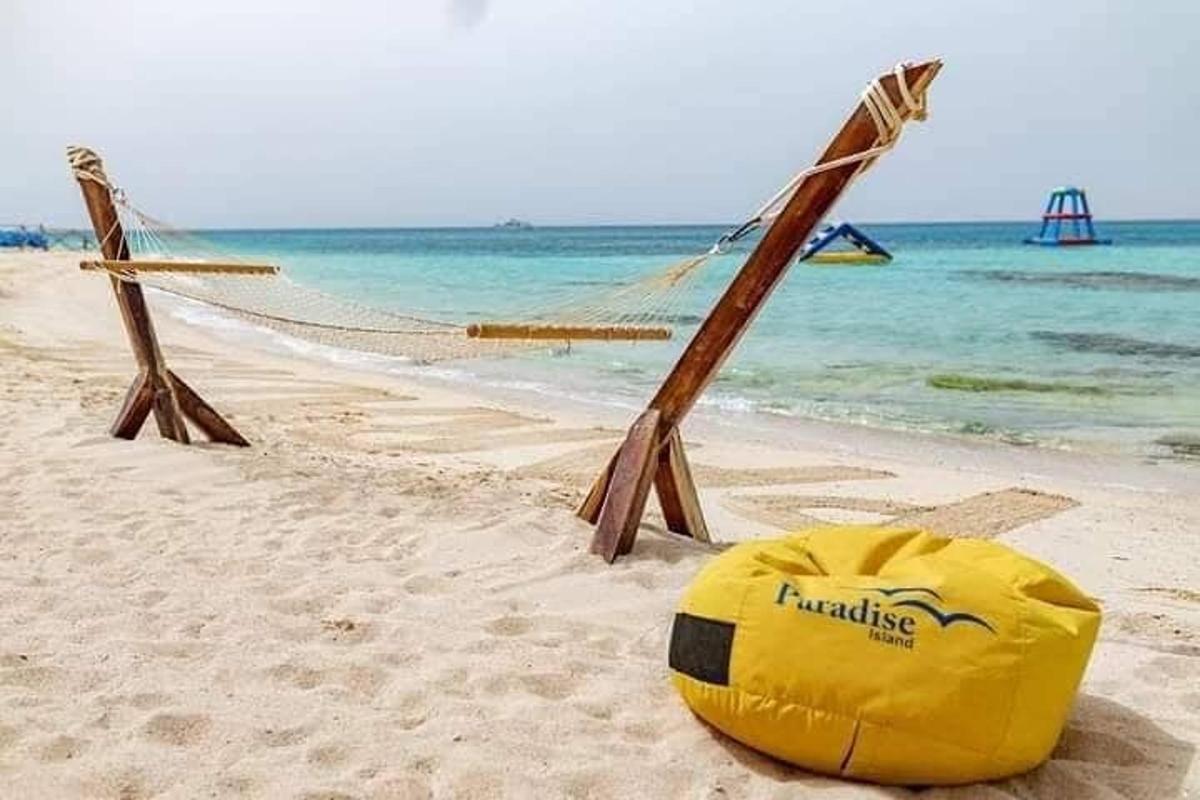 a yellow buoy sitting on a beach with a hammock