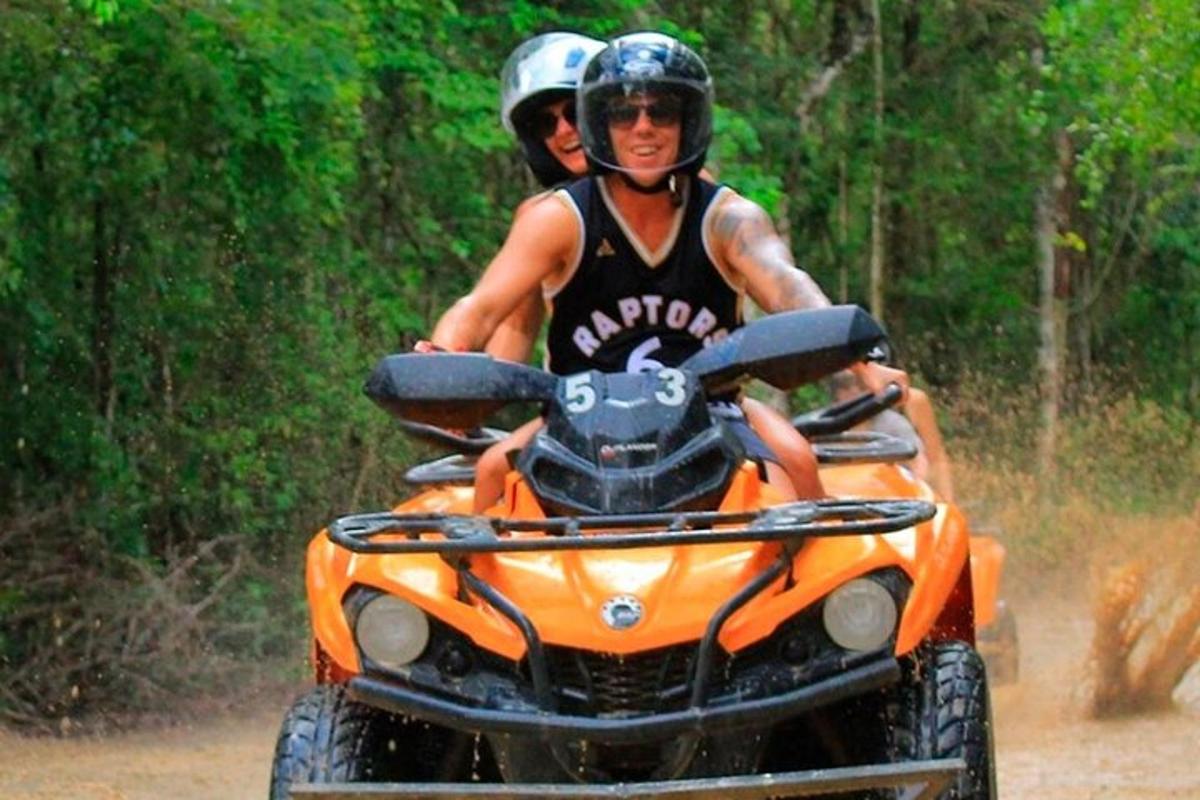 due persone a bordo di un quad arancione su una strada sterrata