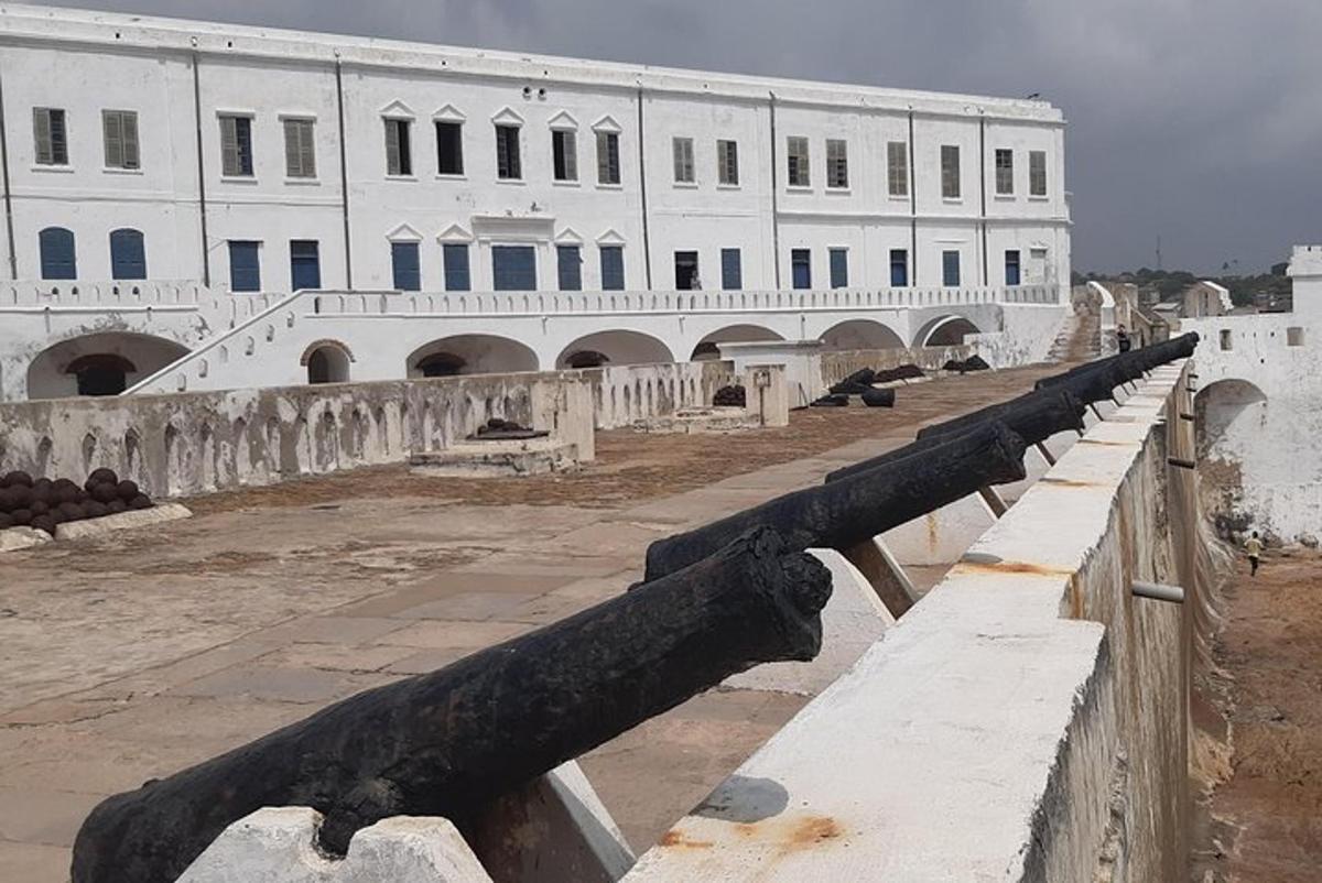 um grande edifício branco com uma fileira de canhões