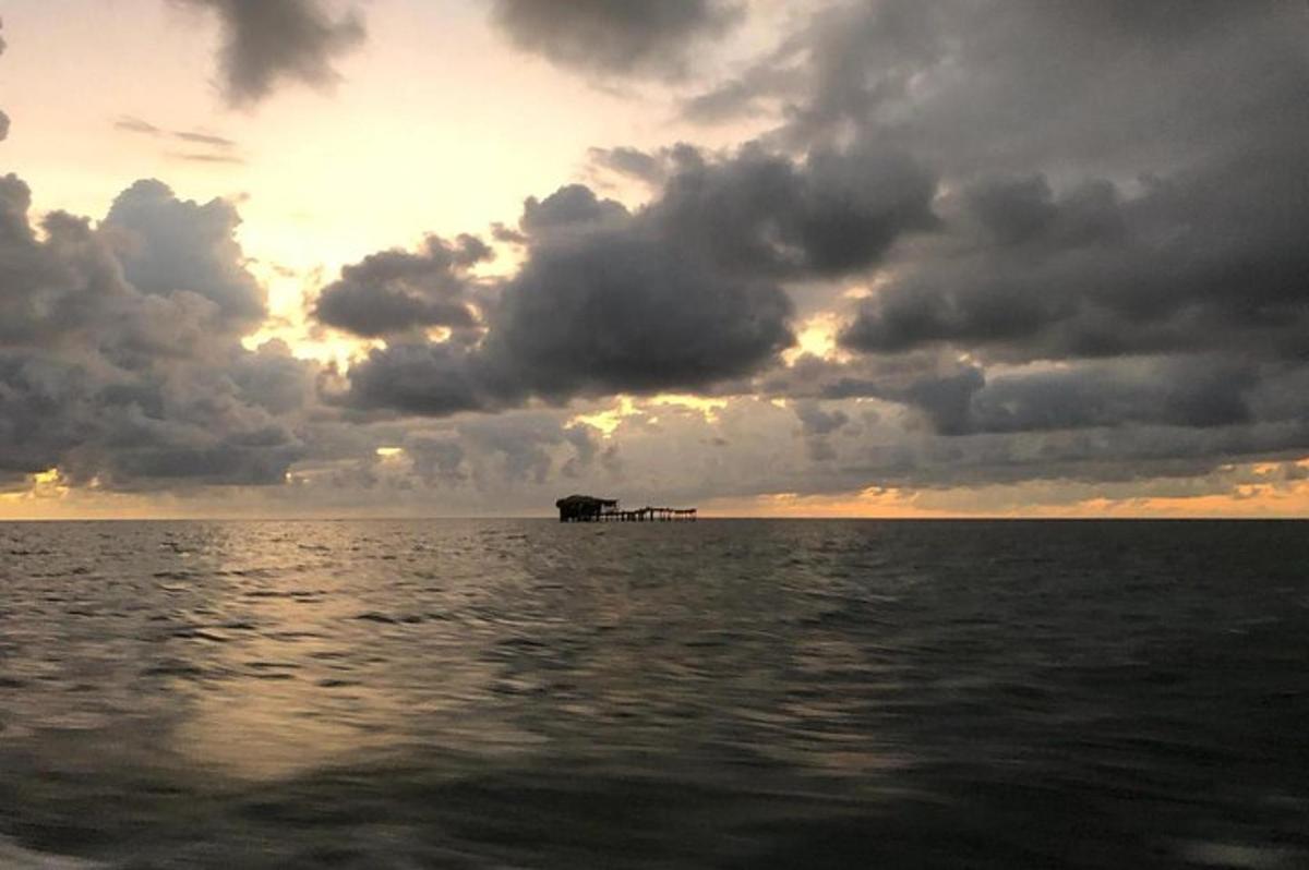 a sunset over the ocean with a pier in the water