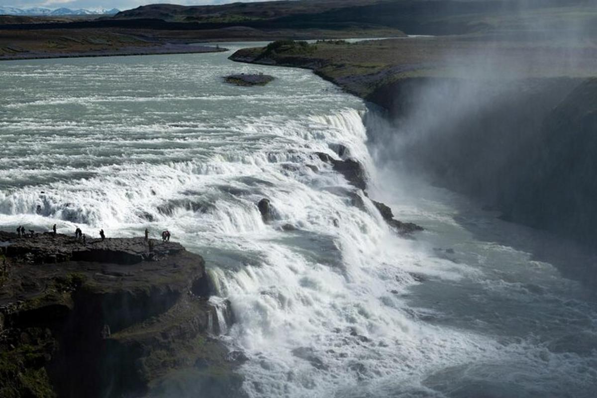 a group of people standing on the edge of a waterfall