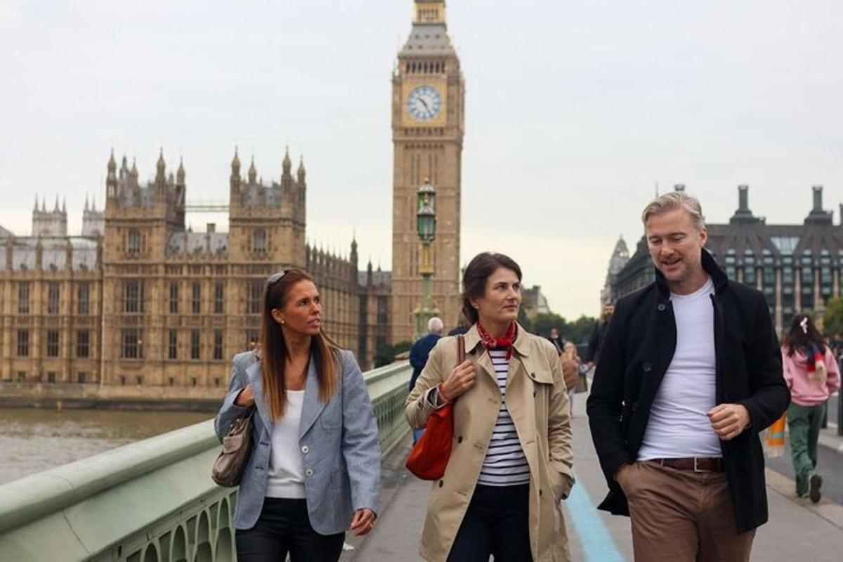 tre persone che camminano su un ponte di fronte al Big Ben