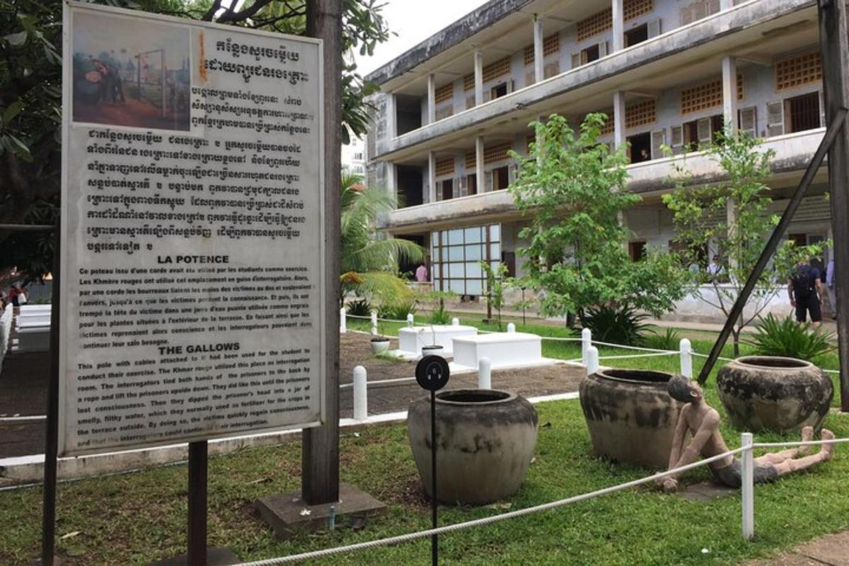 Un cartel delante de un edificio con dos macetas grandes.
