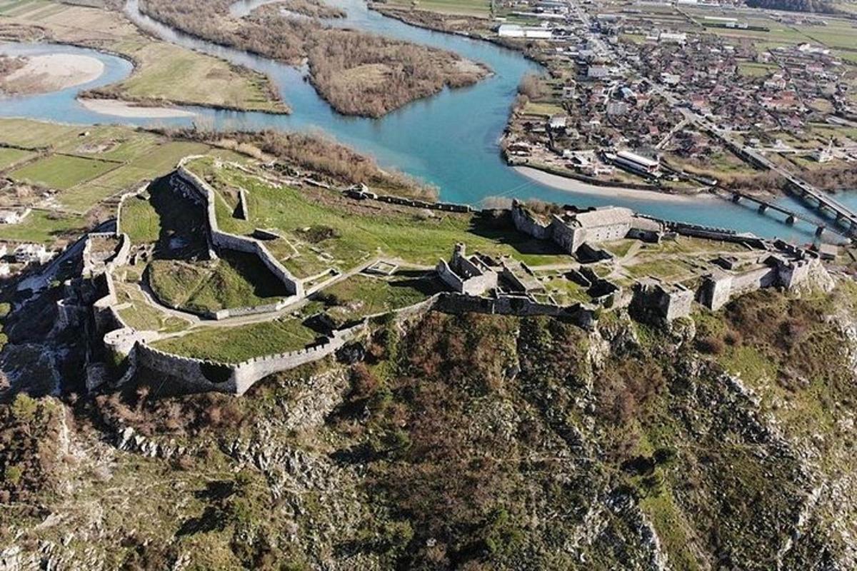een luchtfoto van een kasteel op een heuvel naast een rivier