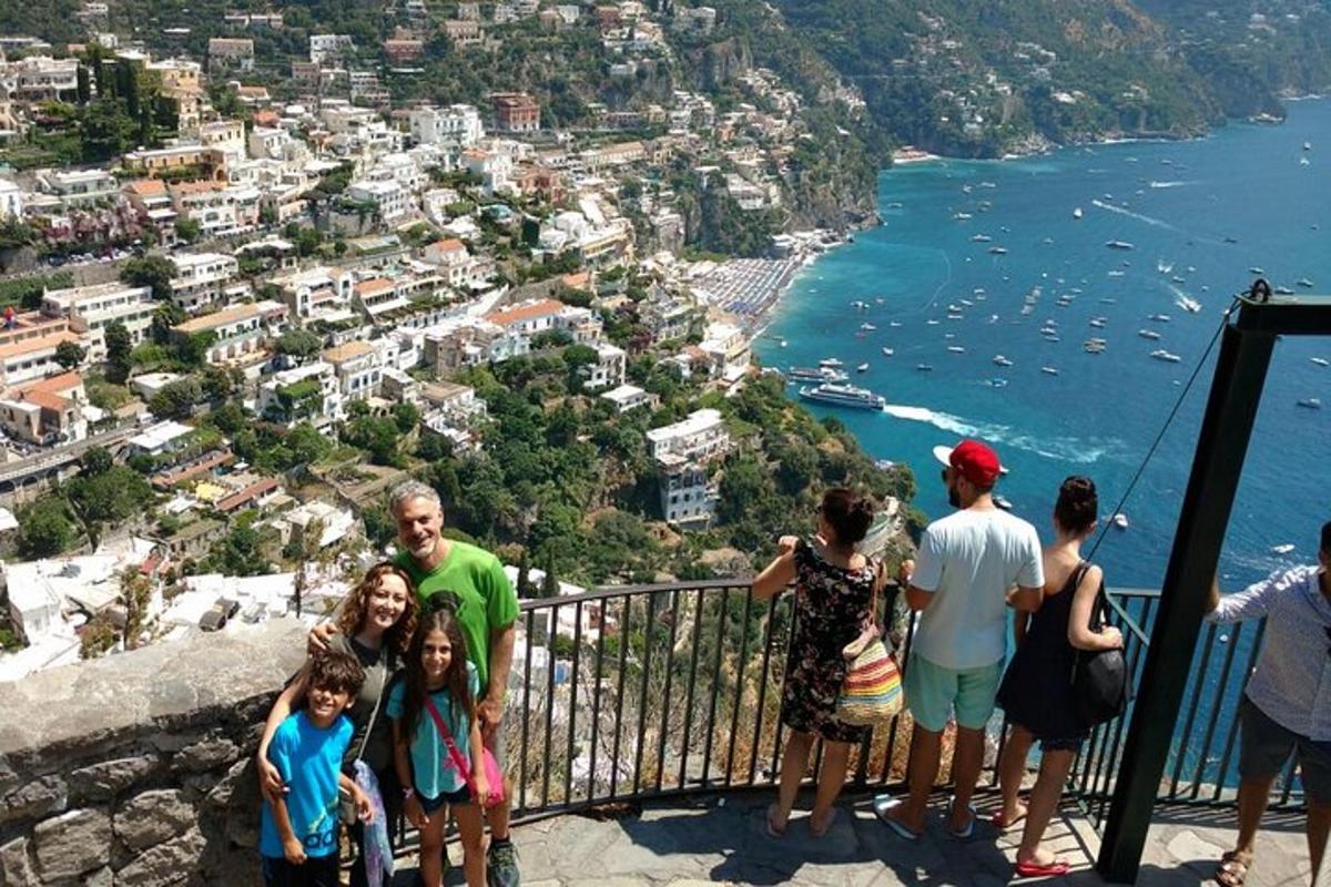 sekumpulan orang berdiri di atas tebing yang menghadap ke pantai amalfi