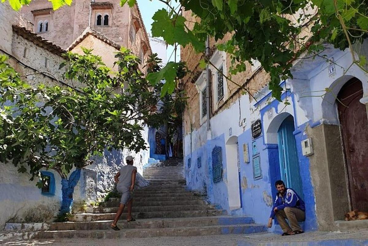 due uomini che camminano lungo un vicolo con edifici blu