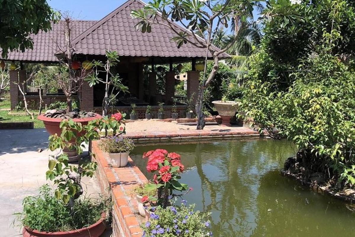 Una casa con un estanque con flores delante.