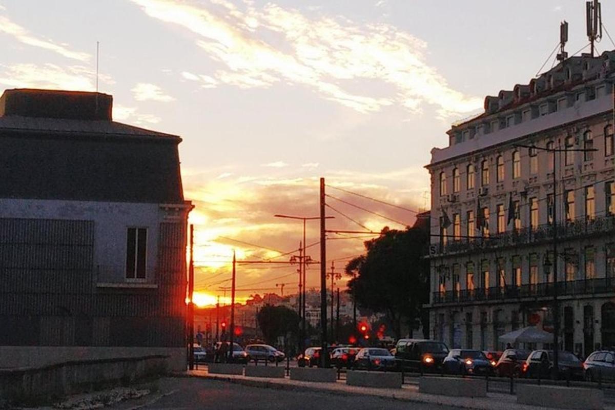 ein Sonnenuntergang in einer Stadt mit auf einer Straße geparkten Autos