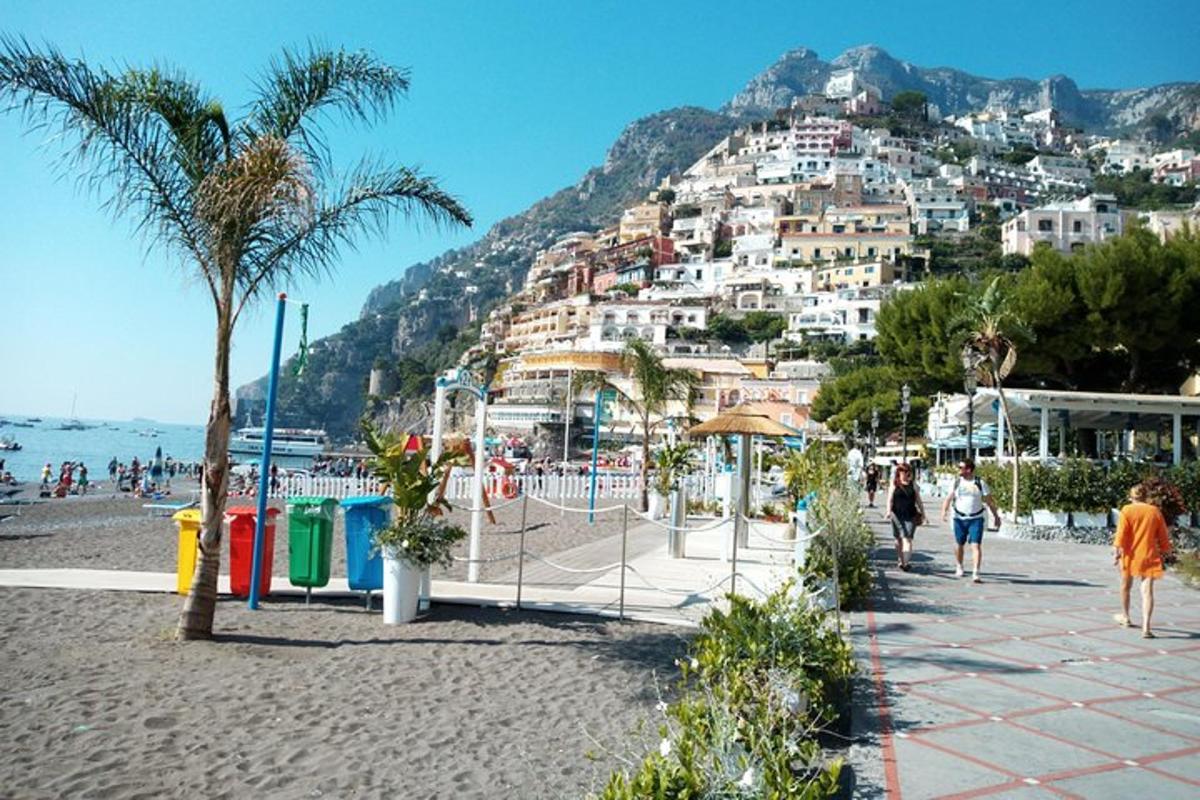 orang berjalan di pantai dengan gunung