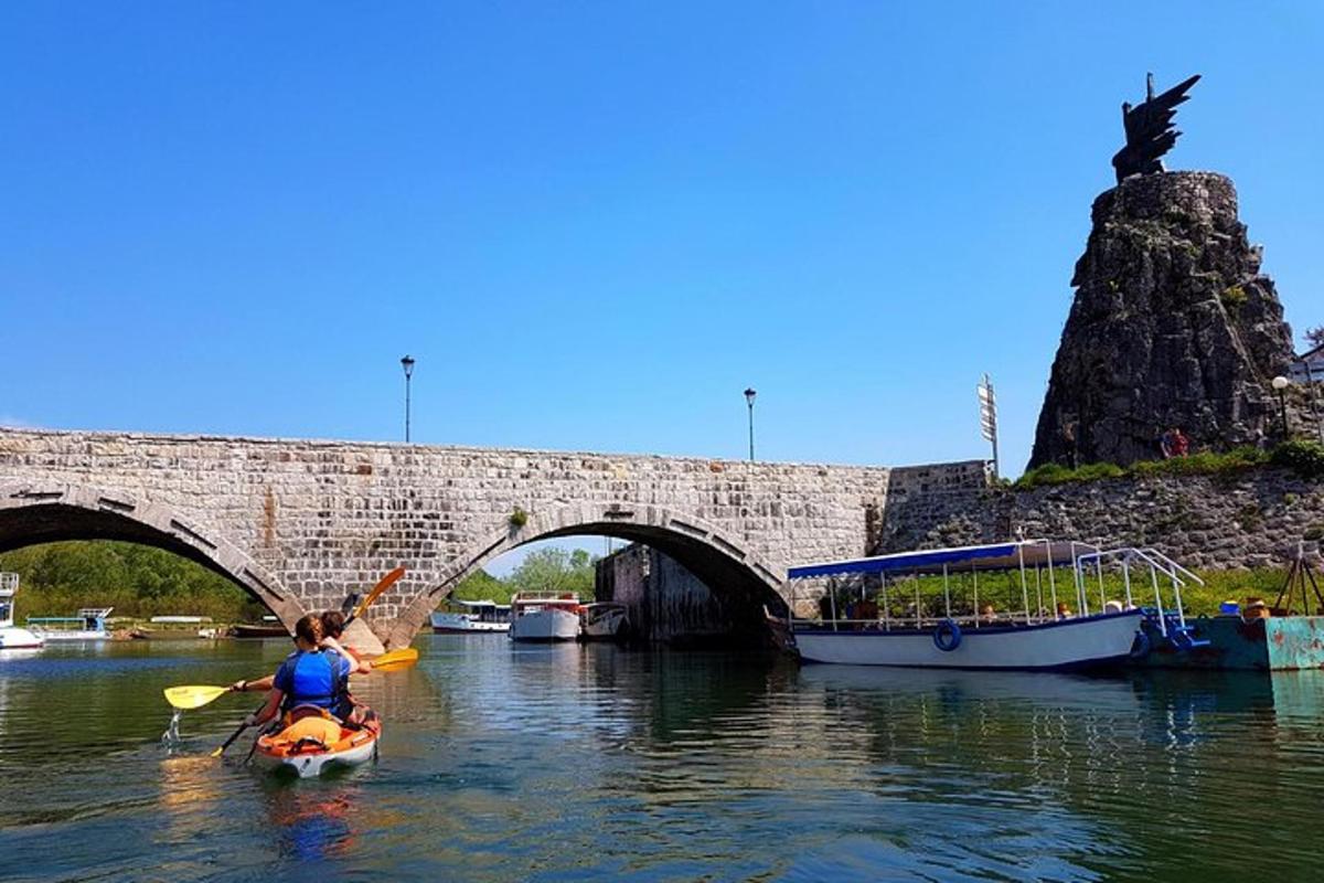 uma pessoa em um caiaque na água perto de uma ponte
