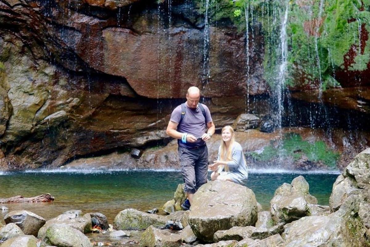 Maður og kona standa á klettum fyrir framan foss