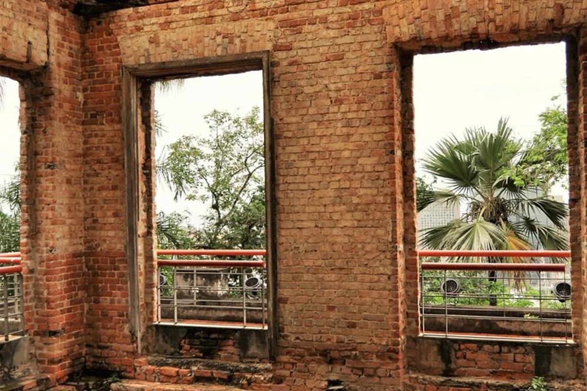 an old brick building with two windows and a palm tree