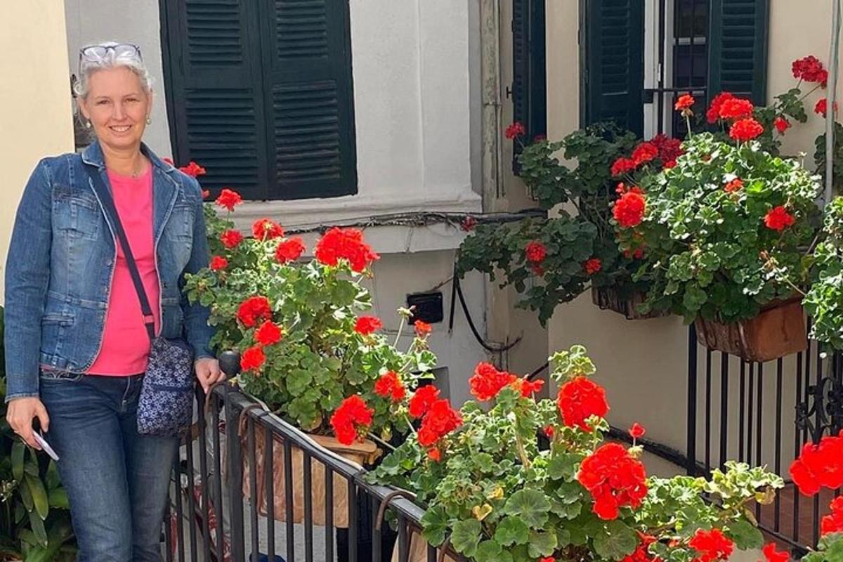 seorang wanita berdiri di balkoni dengan bunga merah