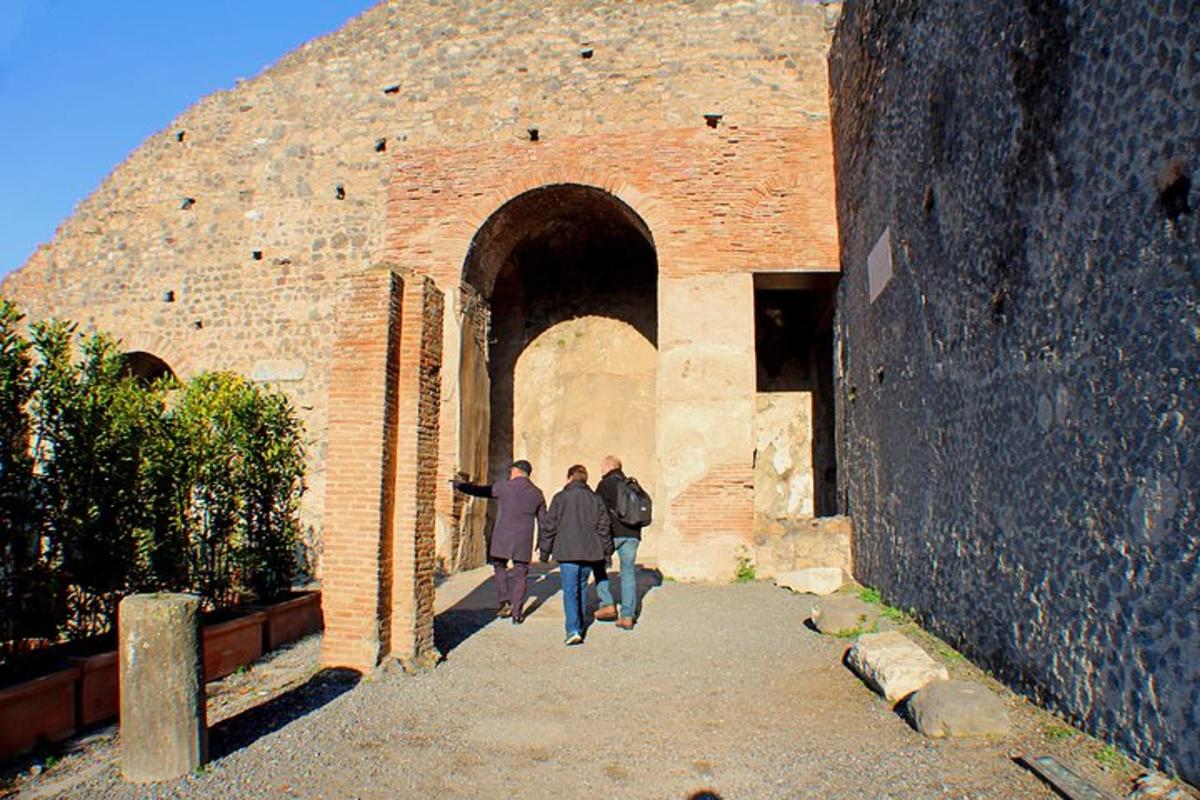 tres persones caminant per un arc en un edifici de maó