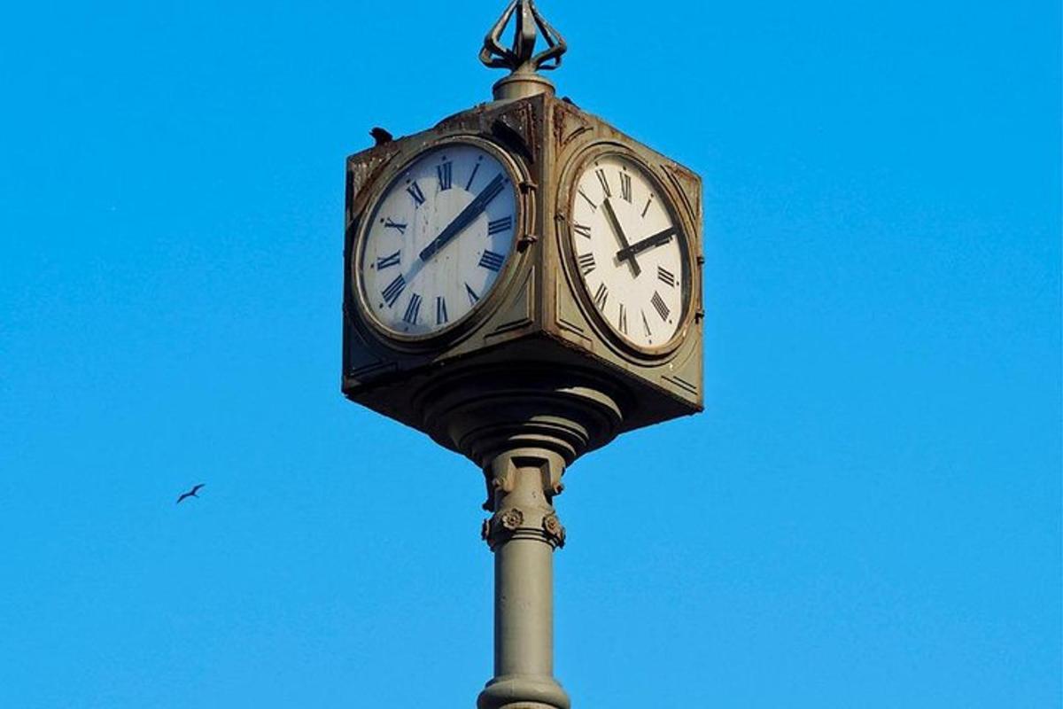 eine Uhr auf einer Stange mit blauem Himmel