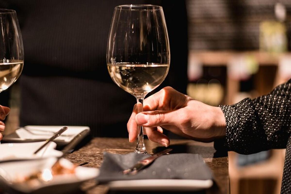 a person holding a glass of wine on a table