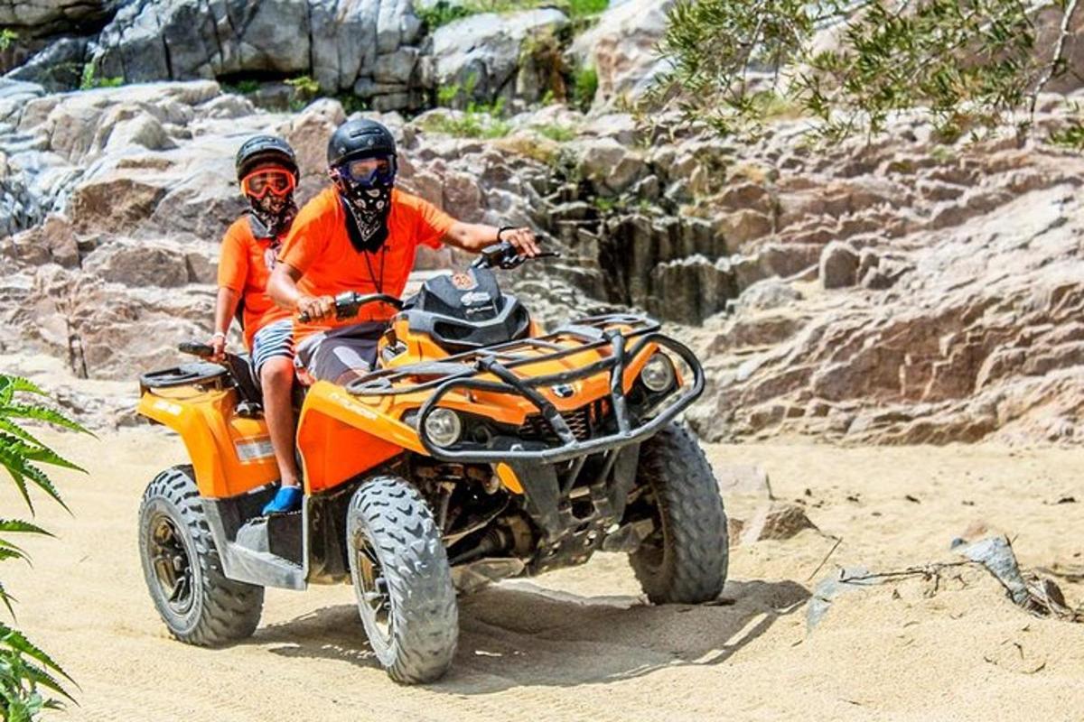 un uomo e un bambino in sella a un quad su una spiaggia