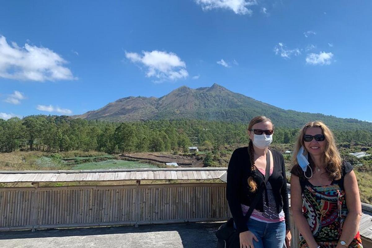 duas mulheres em pé em um telhado com uma montanha ao fundo