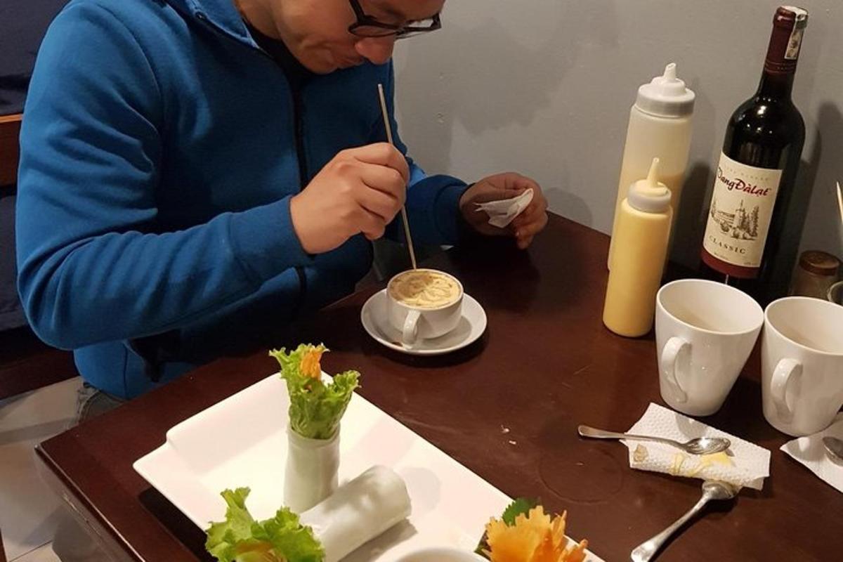 a man sitting at a table eating food with chopsticks