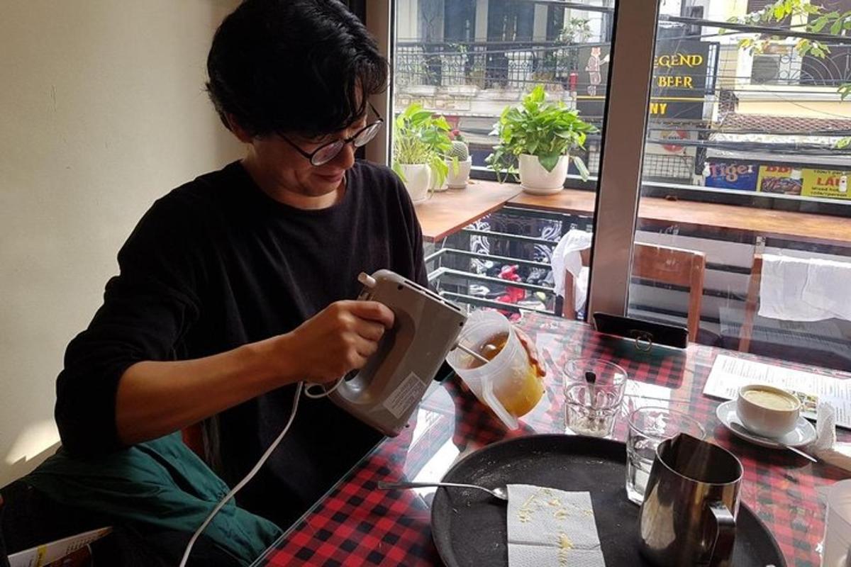 a man sitting at a table in a restaurant using a tea kettle