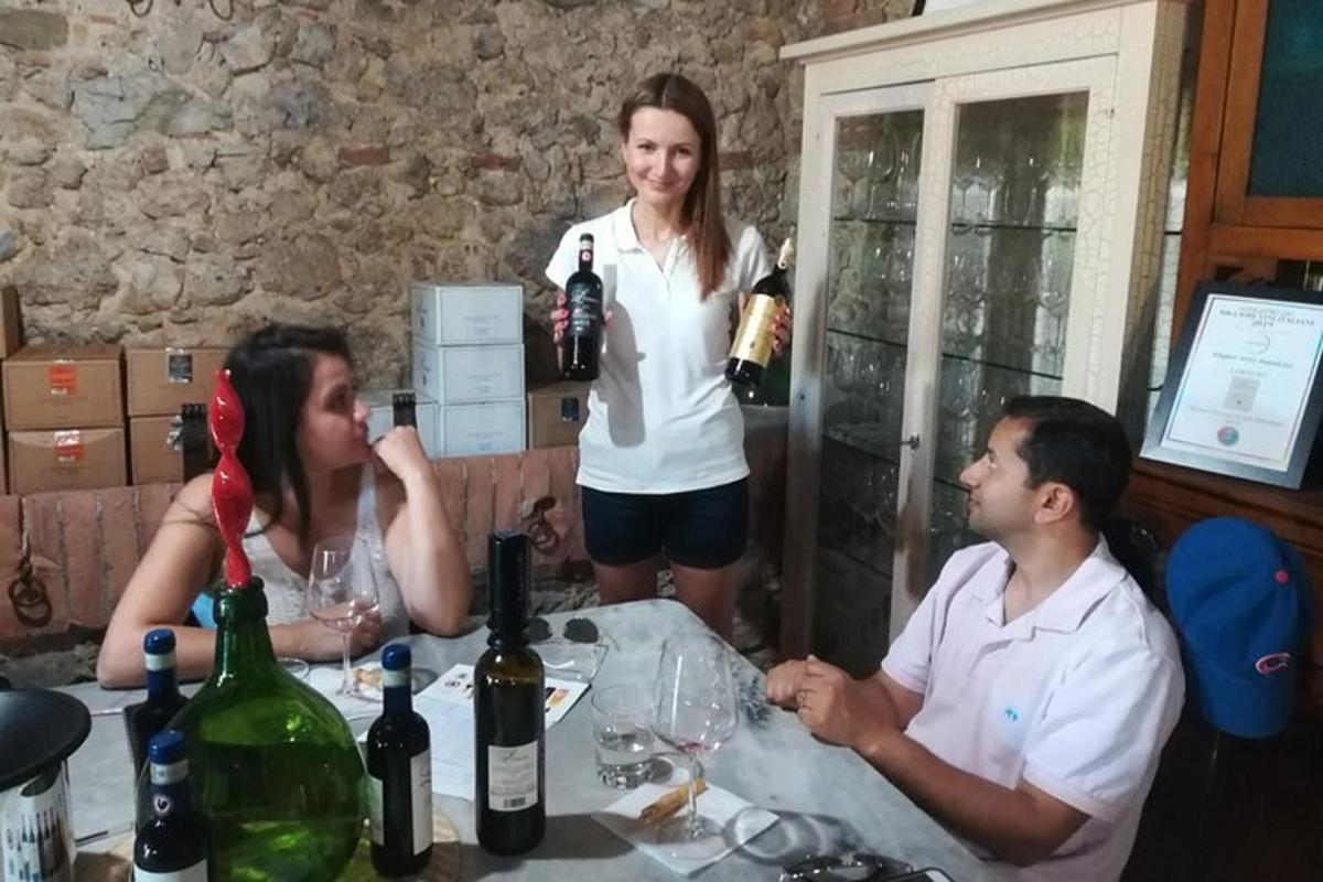 three people sitting at a table with bottles of wine