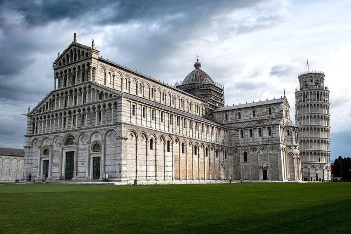 un gran edifici amb una torre inclinada i un camp verd