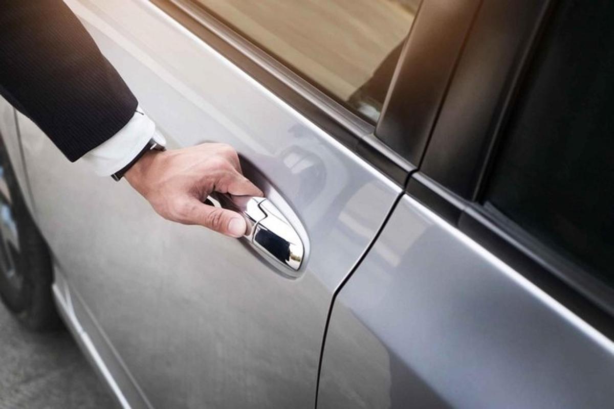 la mano di una persona che tiene la maniglia della portiera di un'auto