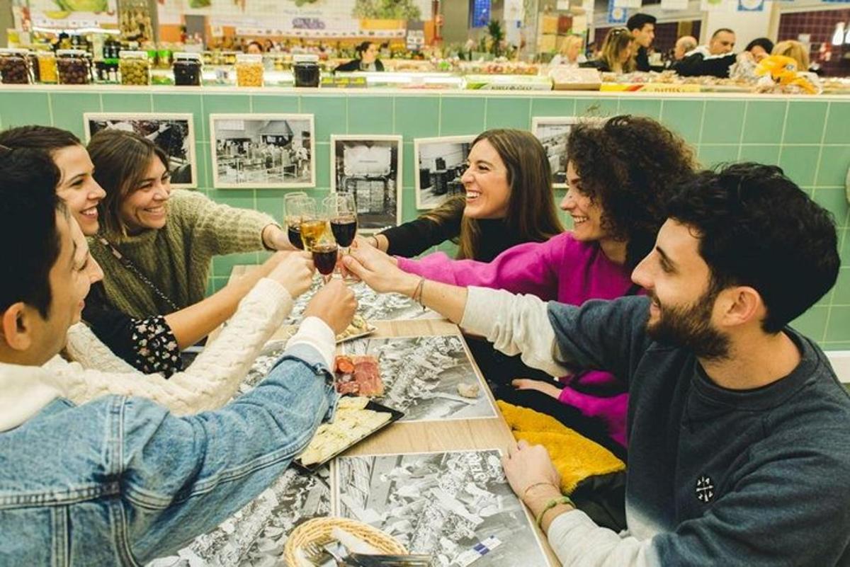 hópur fólks situr við borð og drekkur vín