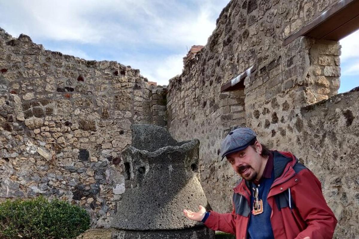 um homem parado em frente a um muro de pedra