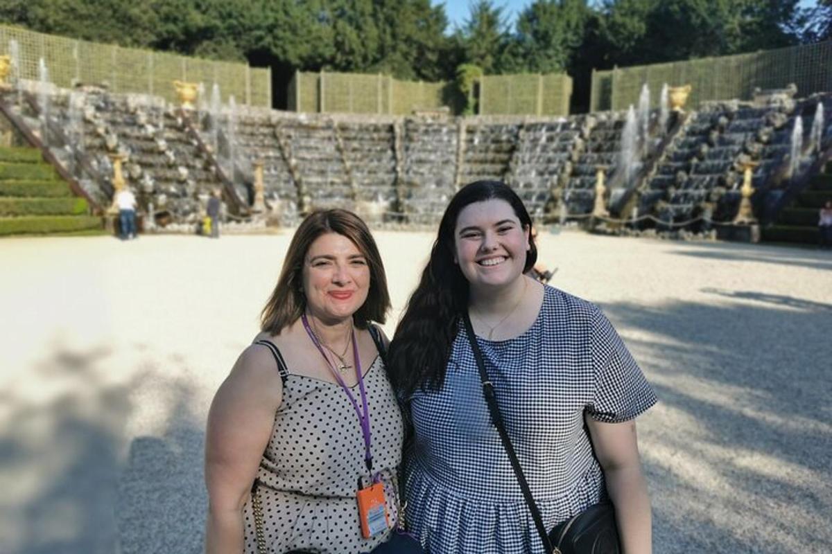 two women are standing in front of a fountain