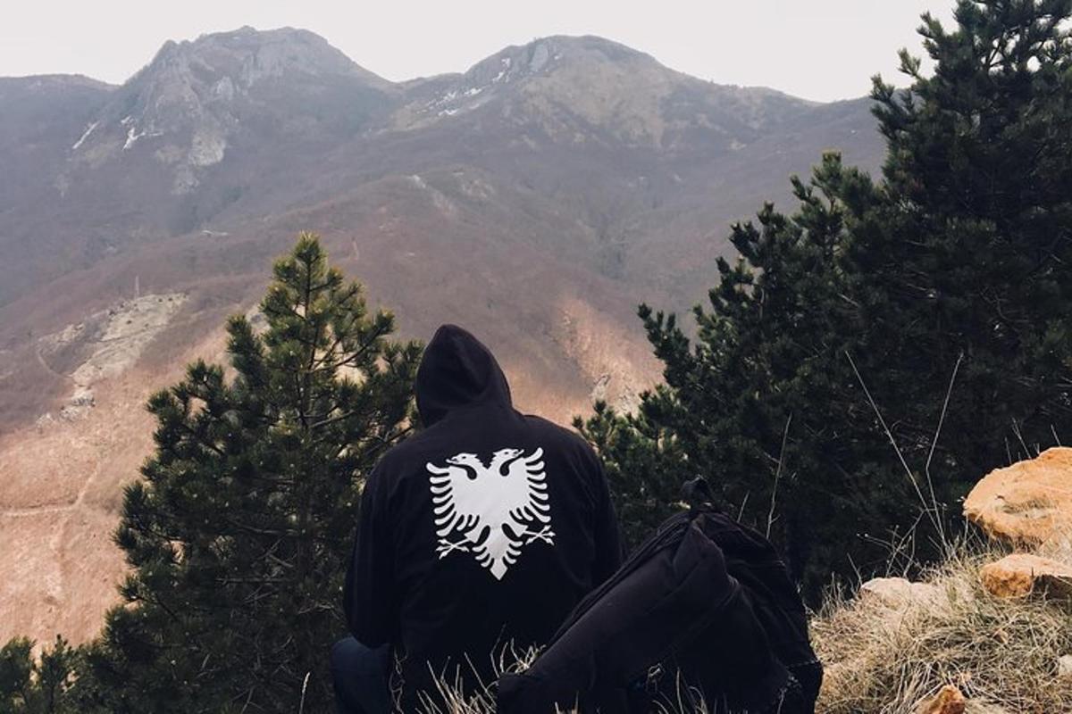 člověk sedící na vrcholu hory a dívající se na hory