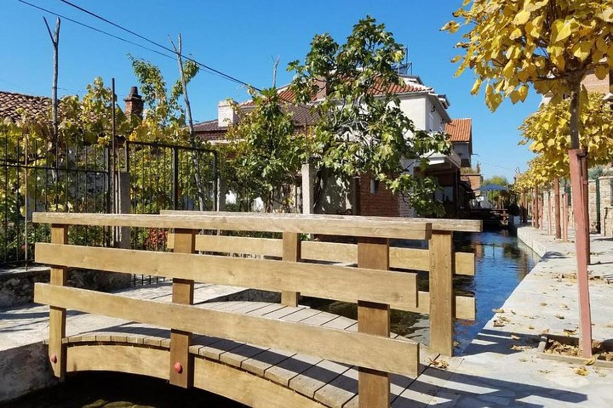 una panchina di legno seduta su un marciapiede accanto a un canale