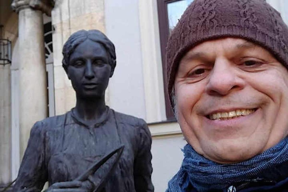 ένας άντρας με καπέλο που στέκεται δίπλα σε ένα άγαλμα