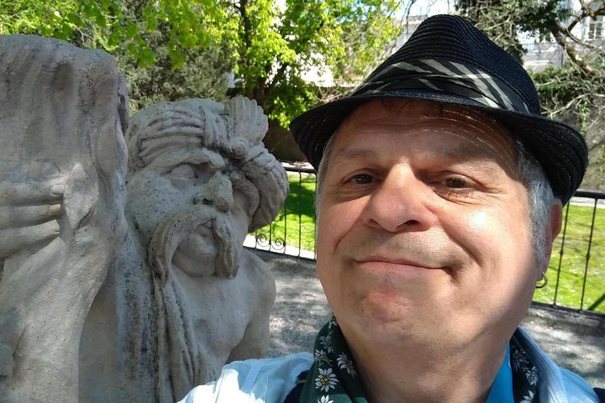 muž v klobouku stojící vedle sochy