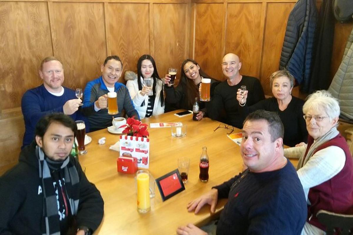 skupina lidí sedících kolem stolu a pijících pivo