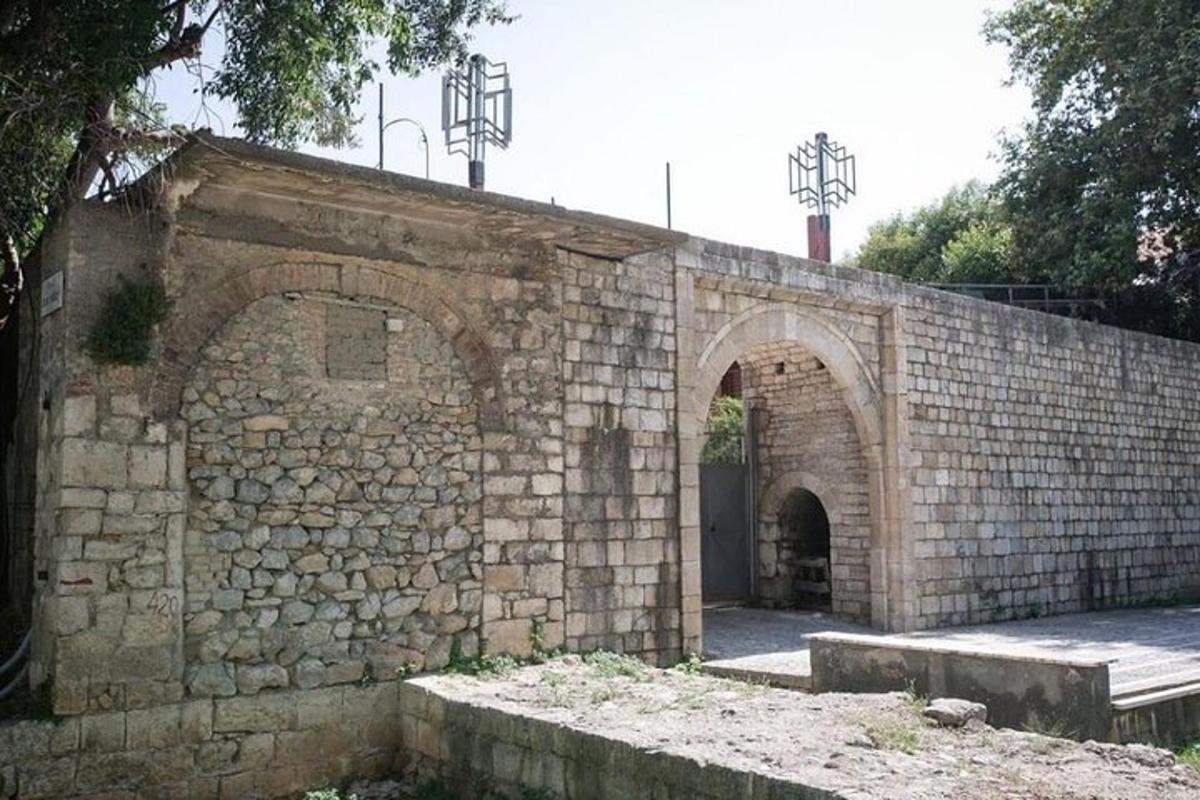 un vecchio muro di mattoni con un arco e due panchine