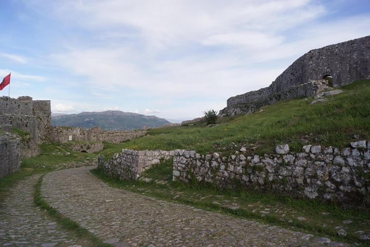 Un muro de piedra junto a una montaña con una bandera.