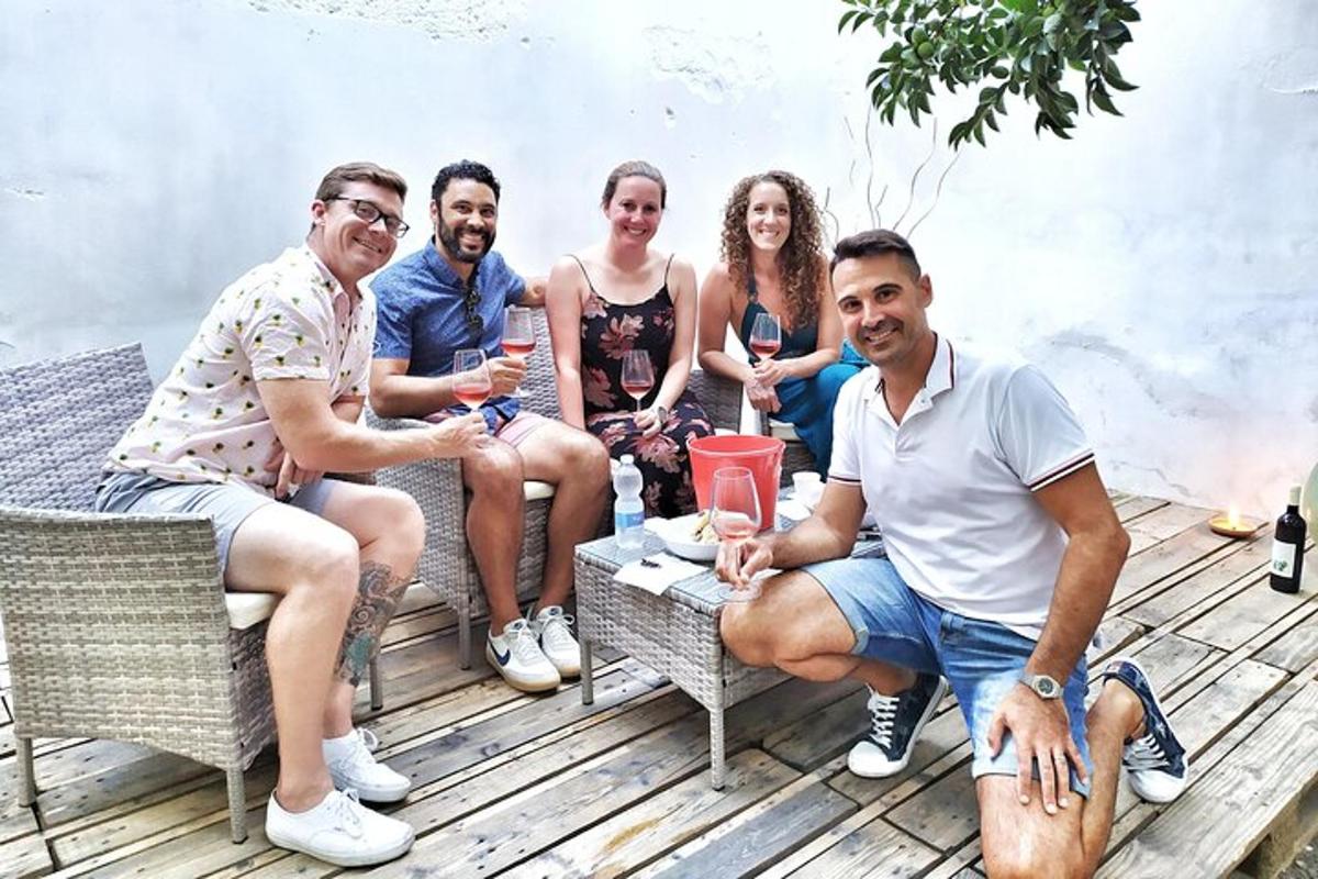 μια ομάδα ανθρώπων που κάθονται σε μια βεράντα πίνοντας κρασί