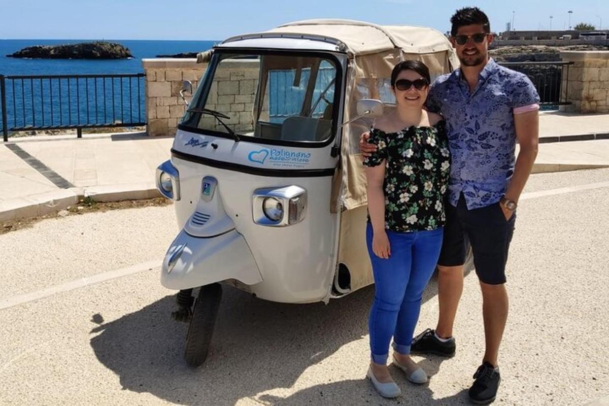 a man and a woman standing next to a small motor scooter