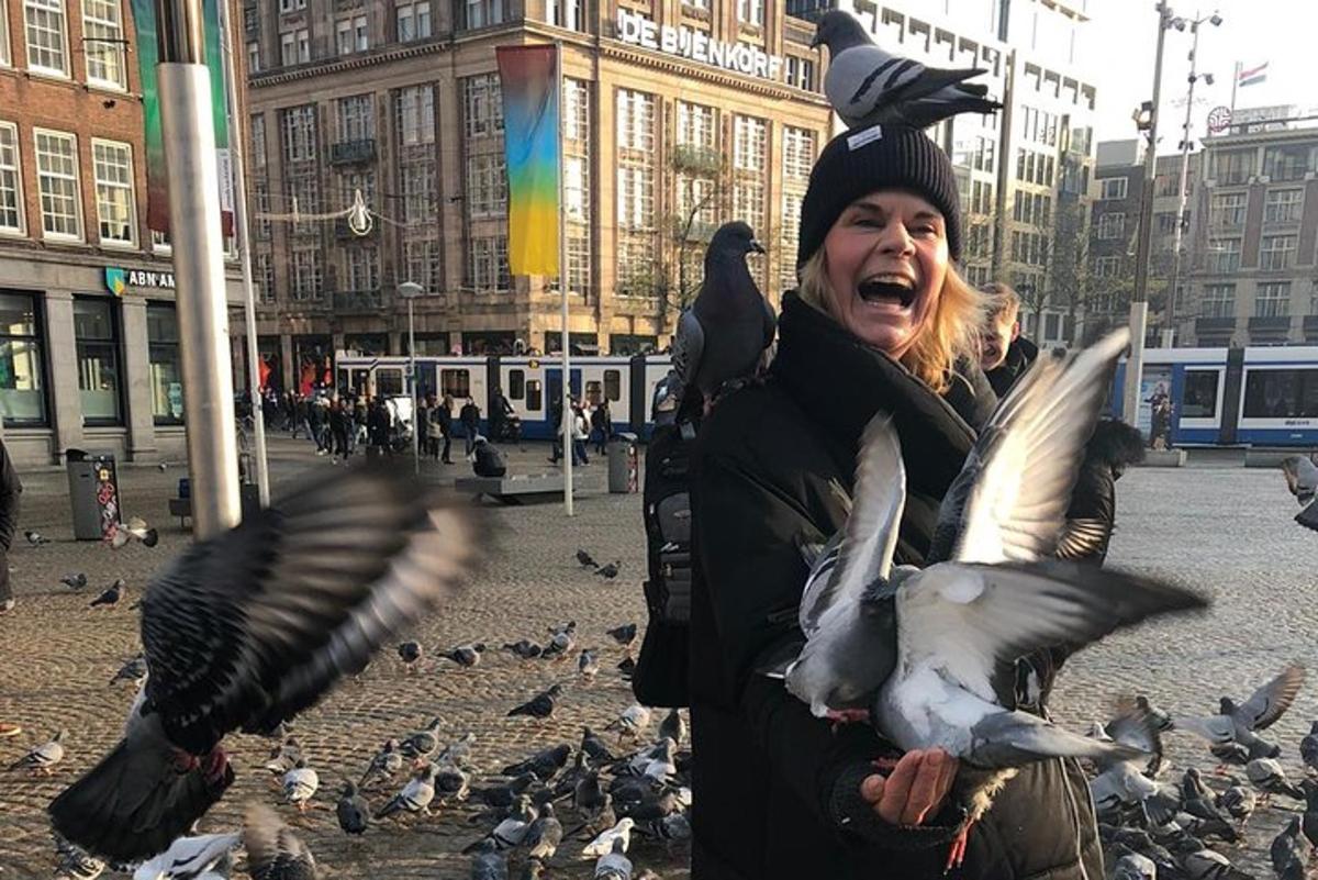 una donna che dà da mangiare ai piccioni in una strada cittadina