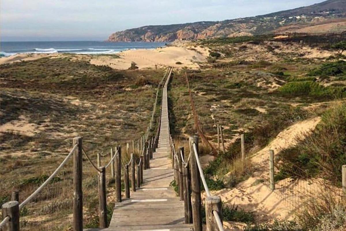 дрвена стаза која води до плаже са океаном