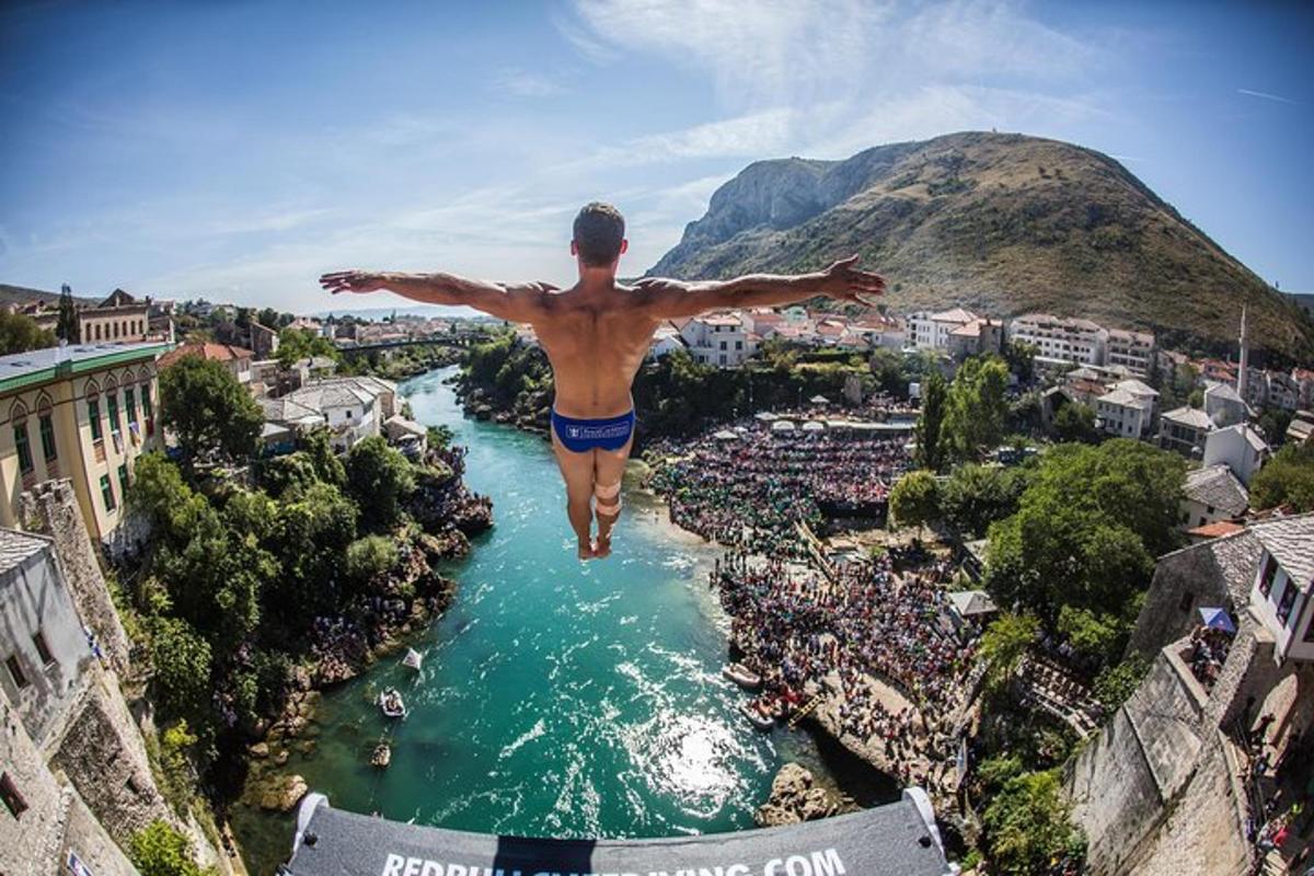 muž skákající do řeky s rozpaženýma rukama