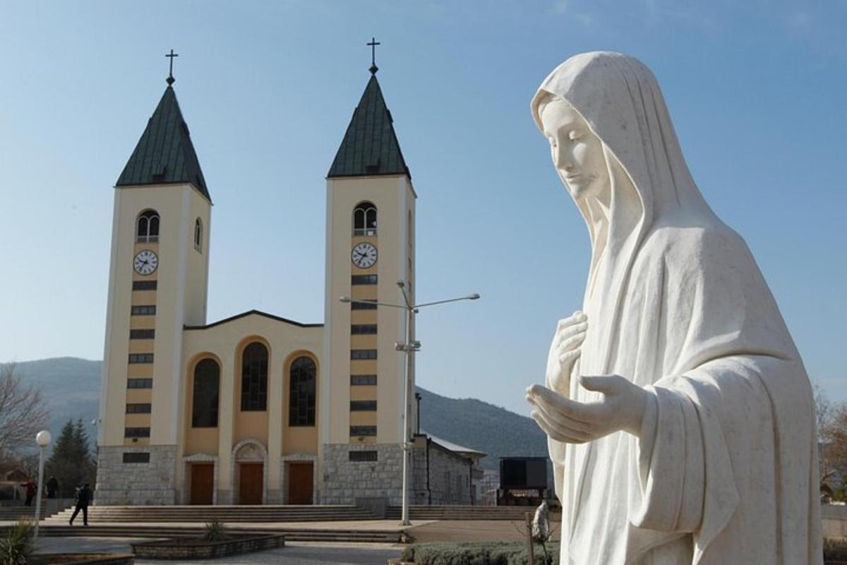 socha před kostelem s hodinovou věží