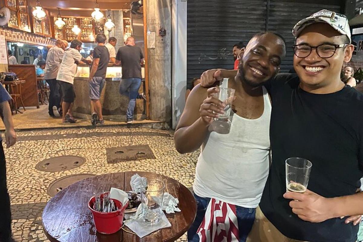 dvaja muži stojaci vedľa stola s pohárom