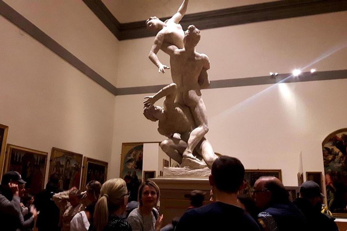ένα άγαλμα δύο ανθρώπων σε ένα δωμάτιο με πλήθος