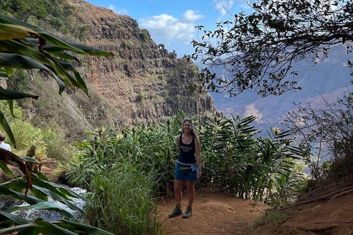 a woman standing on a dirt trail in front of a mountain