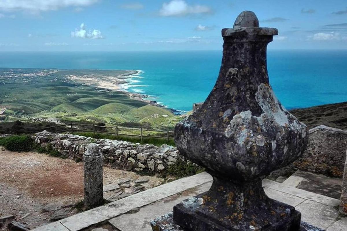 una estàtua al cim d'un turó amb vistes a l'oceà