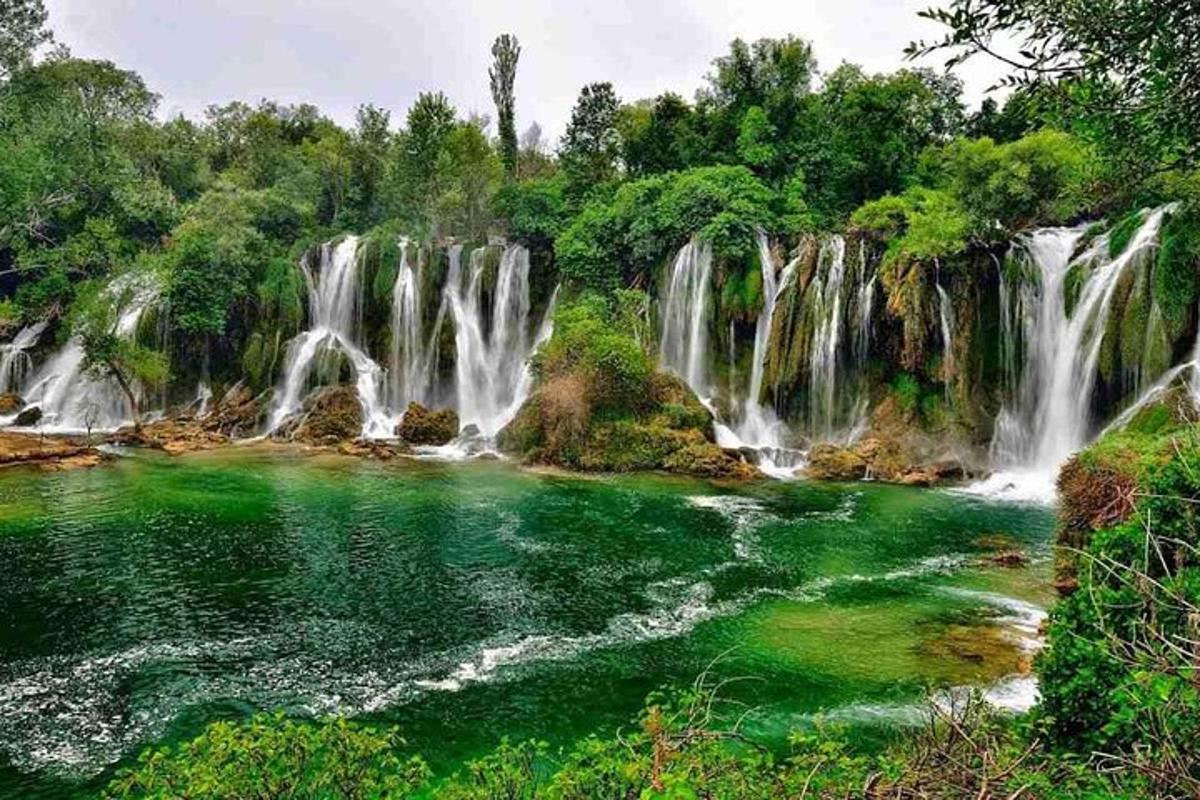 air terjun di tengah sungai dengan air hijau