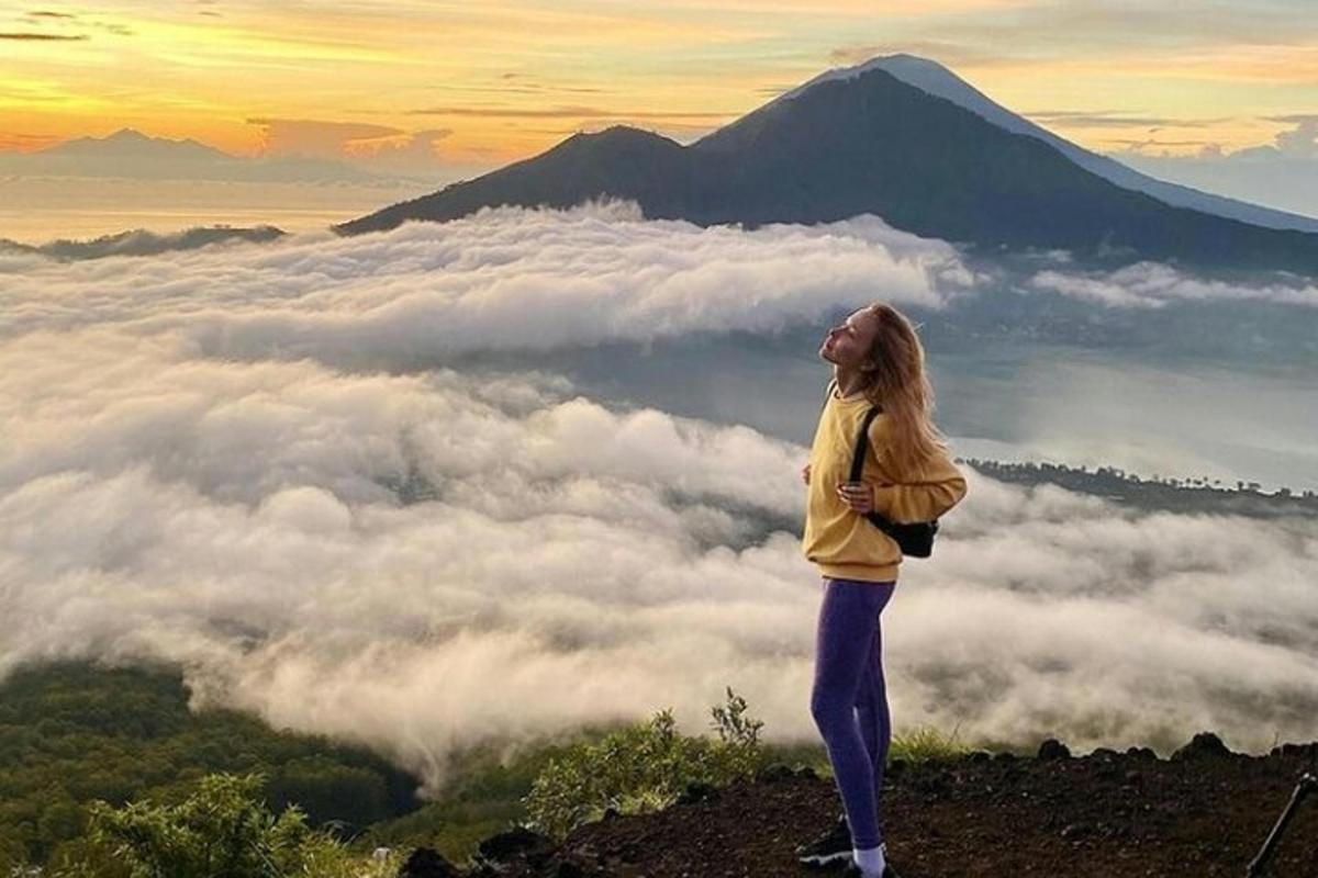 Una mujer parada en la cima de una montaña sobre las nubes.