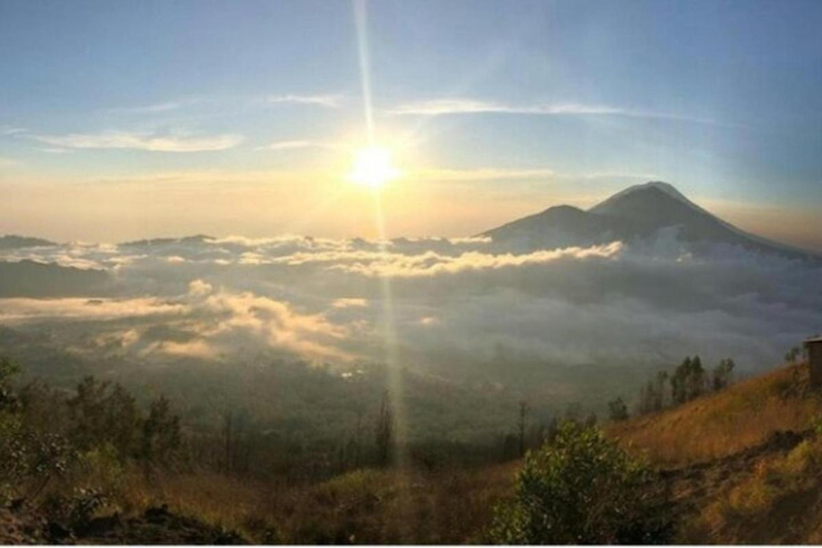 Una vista de una montaña con el sol sobre las nubes.